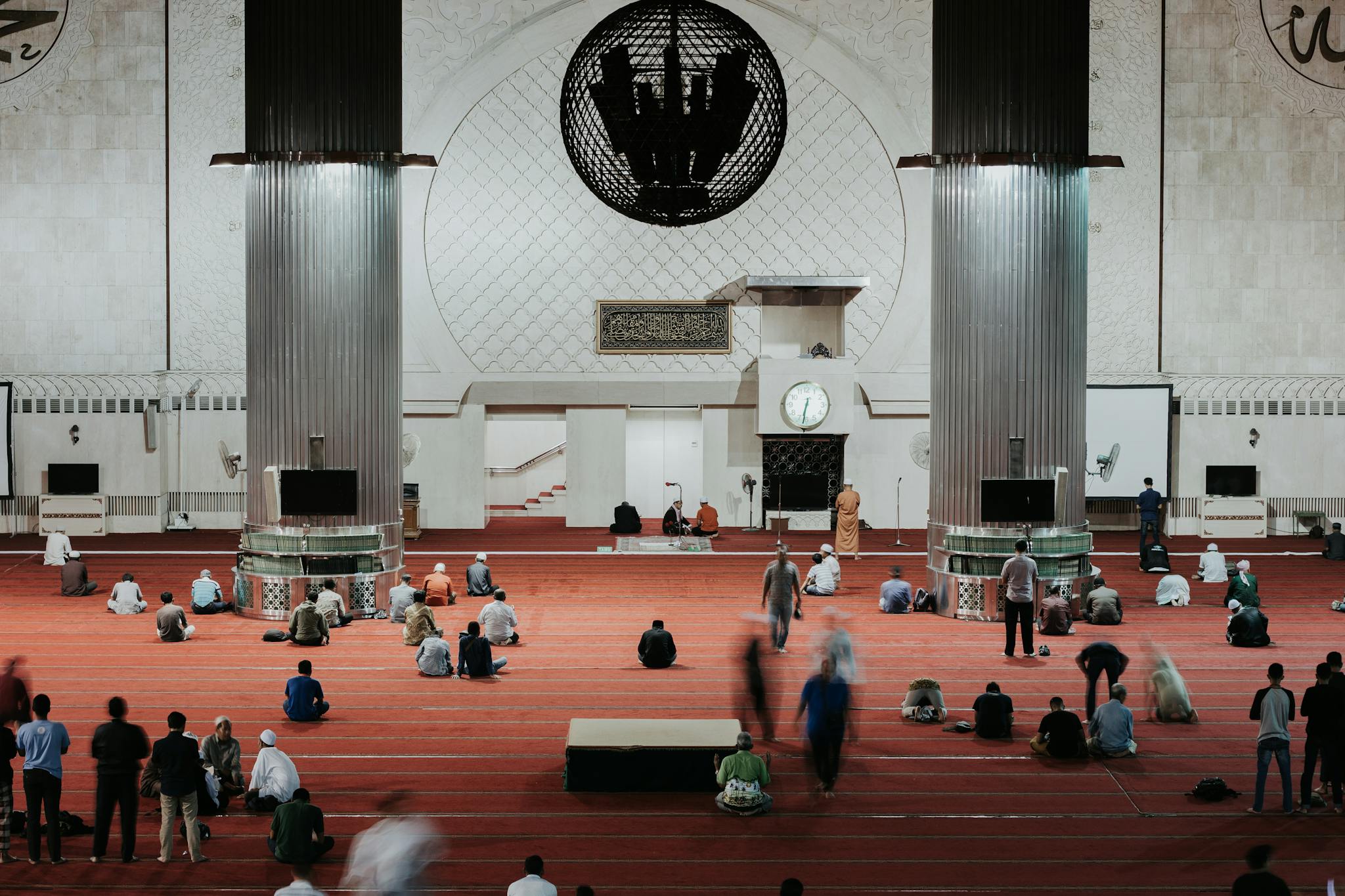 Worshippers gathered in a grand mosque for prayer, showcasing Islamic architecture and community gathering.